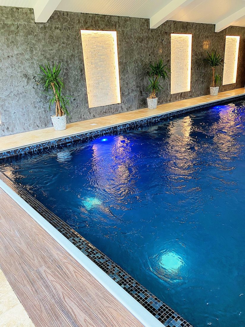 Indoor pool with lit wall alcoves and plants