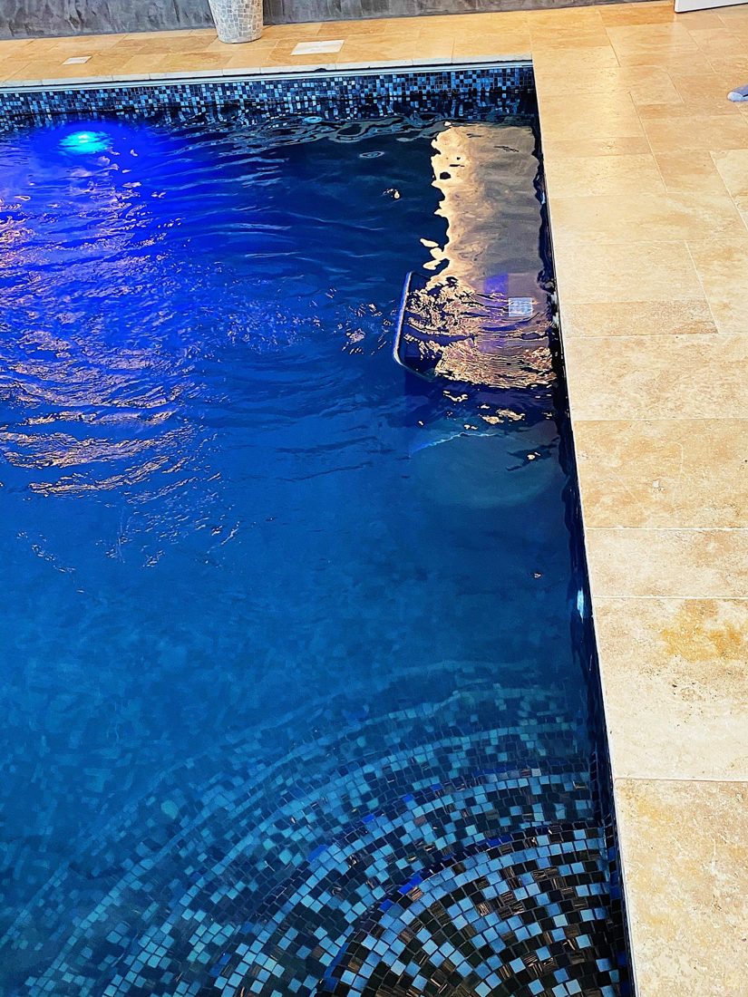 Pool with a lit mosaic edge and stone surround